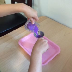 A Practical Life work wherein children develop coordination and focus by pouring sand through a funnel. For variety, the funnel sizes and sand colors may change with time.