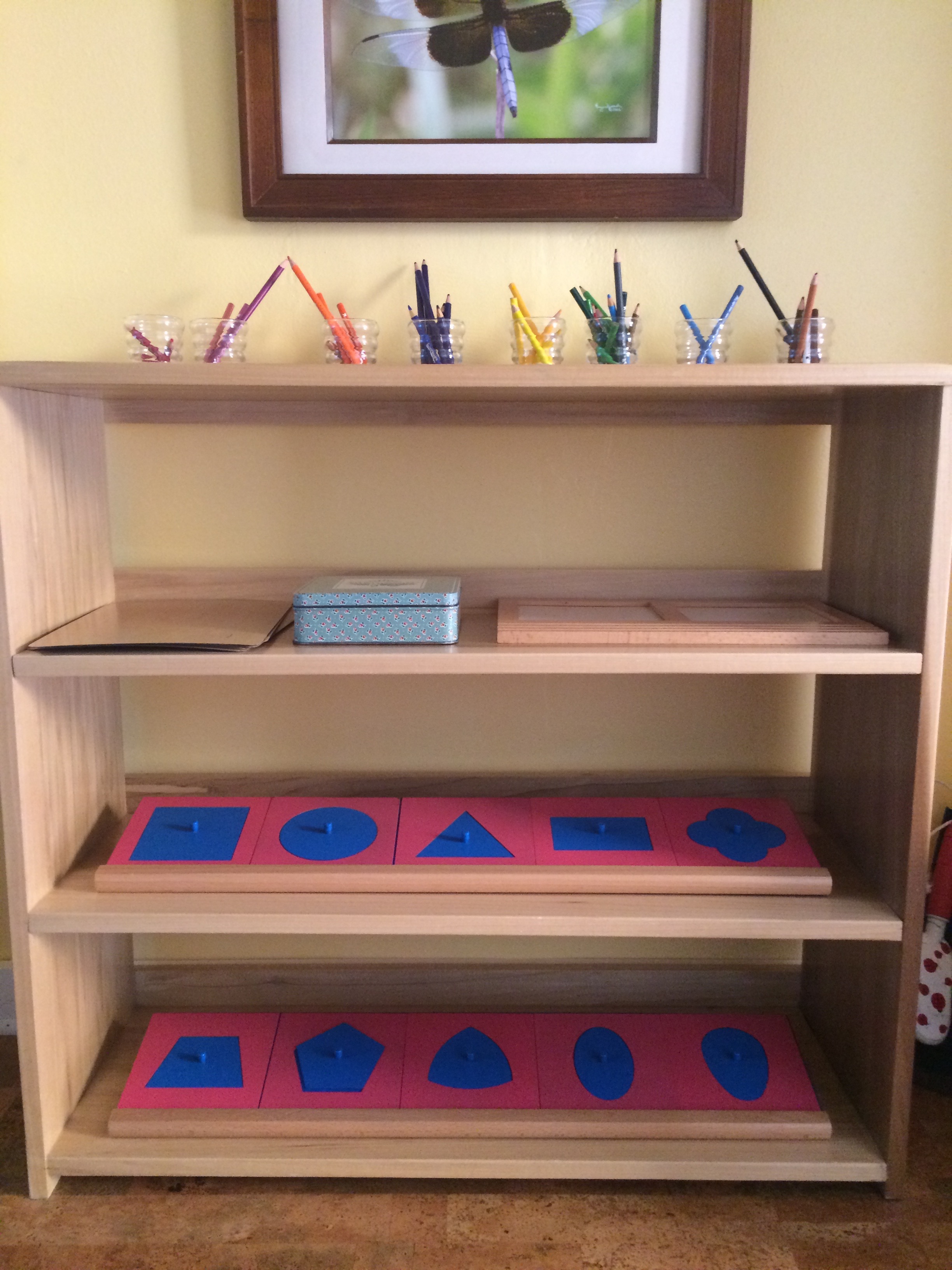 This custom-made shelf includes pencils, paper, trays and the pink frames and the blue insets.